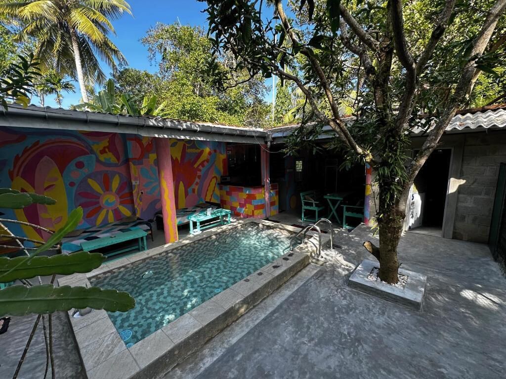 A swimming pool with a colorful mural, a small table, and a tree.