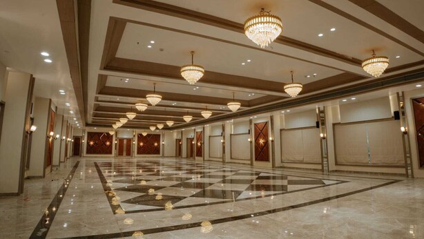 A spacious hotel lobby with a checkered floor, multiple doors, and chandeliers.