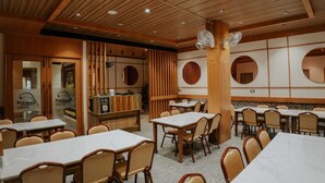 A restaurant interior with wooden ceiling panels, round mirrors, and multiple dining tables and chairs.