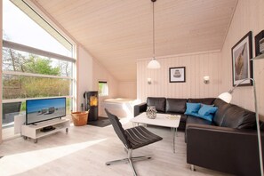 A modern living room with a television, a fireplace, a sofa, and a dining table. - Nordische Familienentflucht mit Sauna (Grossenbrode)