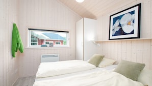 Una habitación con dos camas, una ventana, un radiador y un cuadro en la pared.