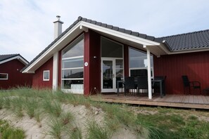 A house with a large glass door, a deck with outdoor furniture, and a number 72 sign. - Resort-wellnesshaus fur 8 Personen (Grossenbrode)