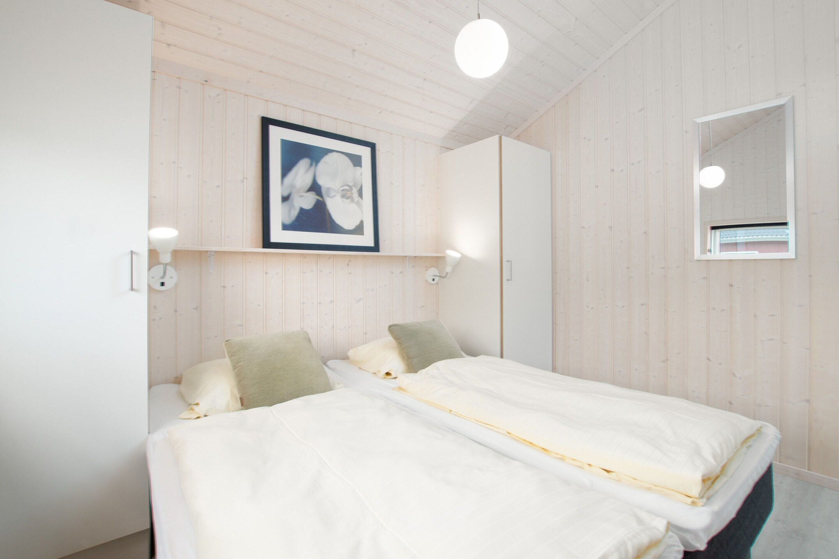 A bedroom with two beds, a framed picture on the wall, and a mirror.