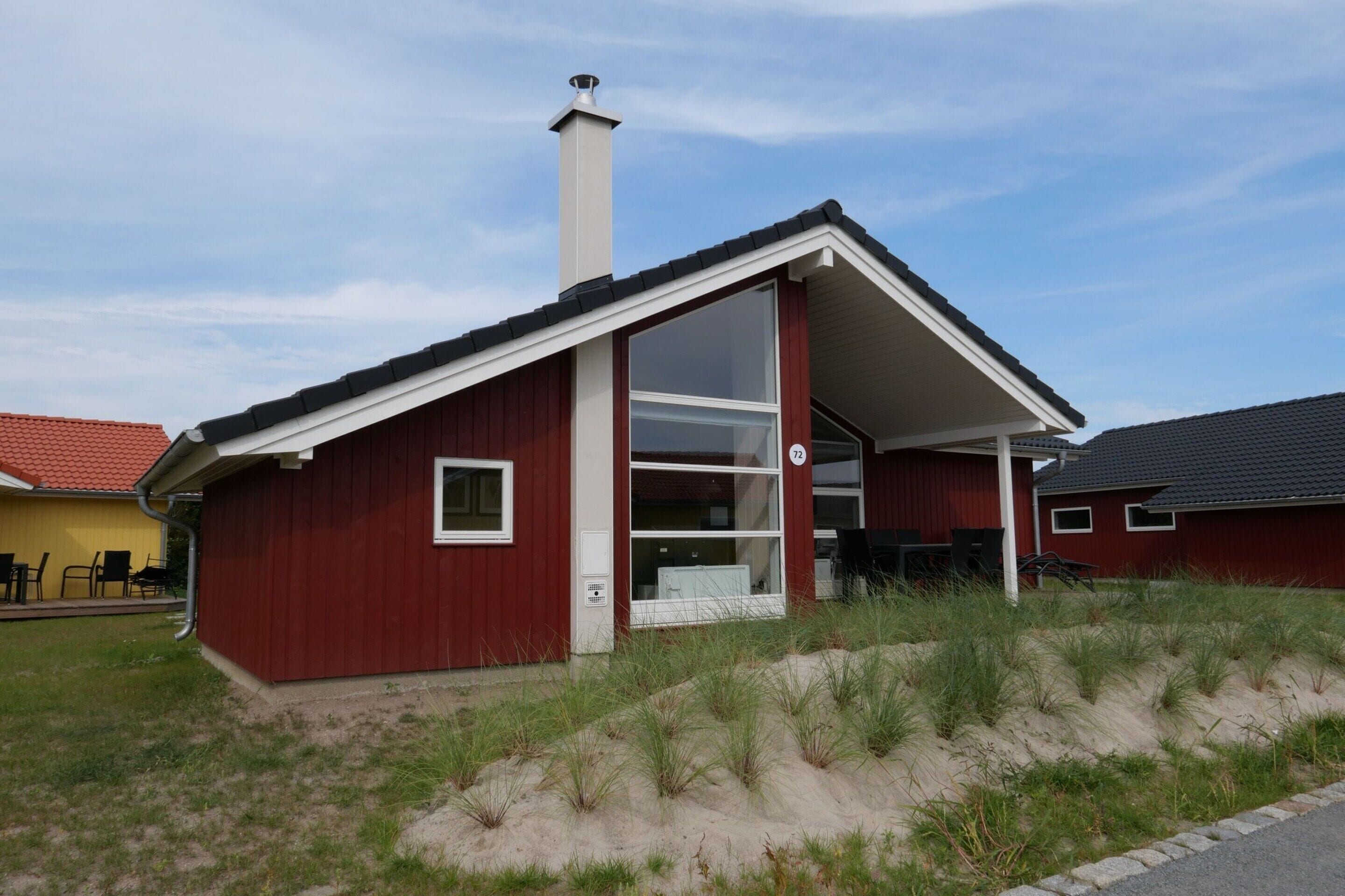 A red single-story house with a large glass door and a chimney.