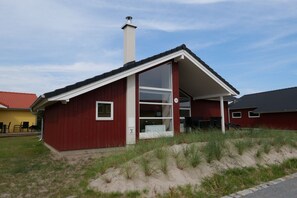 Ein rotes Einfamilienhaus mit einem großen Glasbalkon und einem Schornstein.