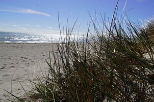 A beach with sand and grass in the foreground.
