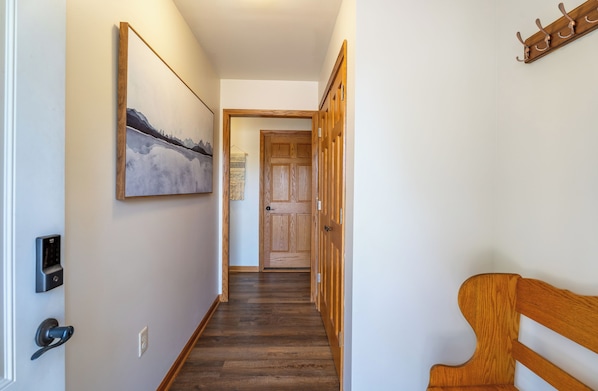 A hallway with a wooden door, a coat rack, and a painting on the wall.
