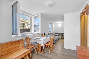 Ein kompakter Wohnbereich mit Essplatz, einer Couch und einer Holzbänkl.