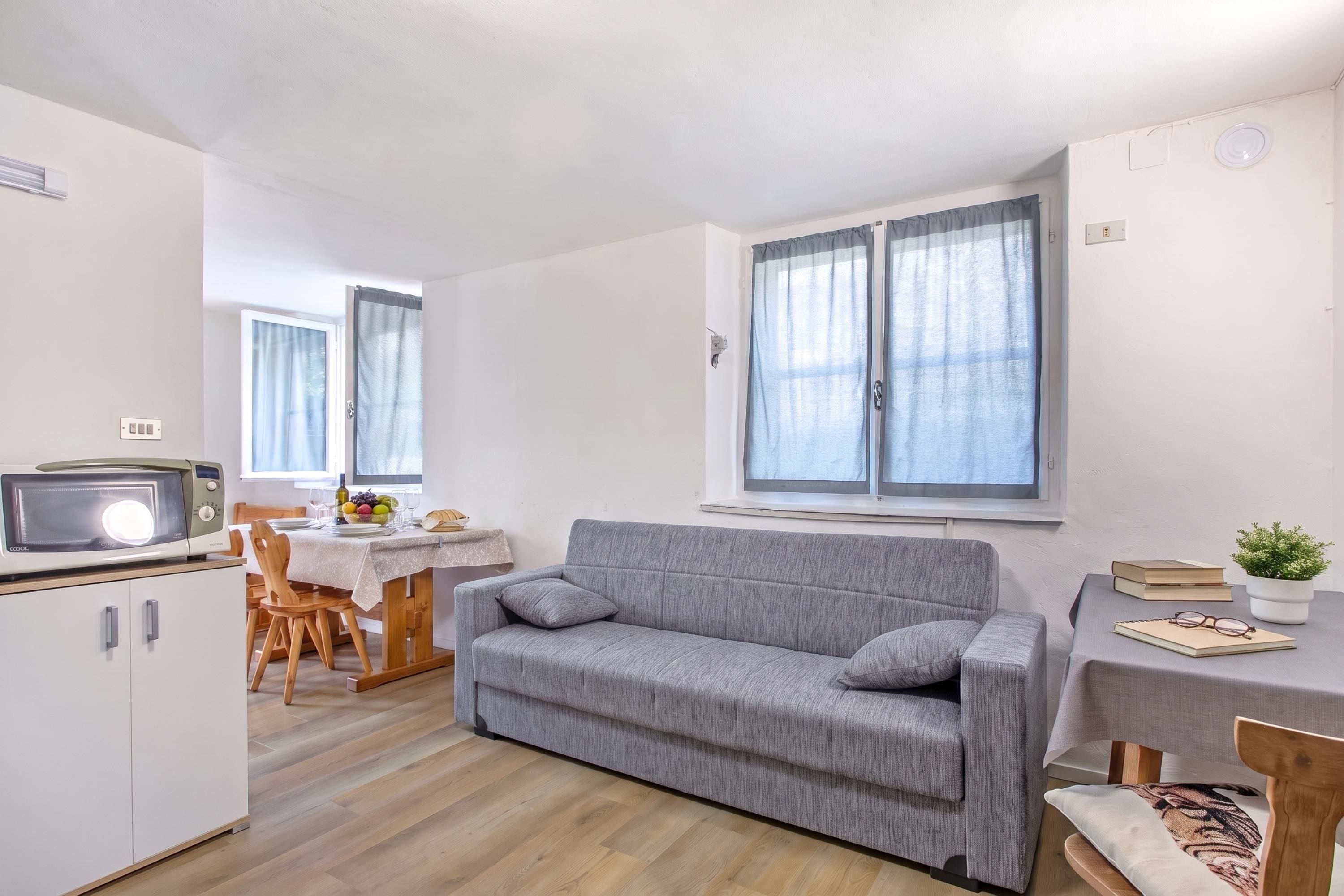 Ein kompakter Wohnraum mit Küchenzeile, Essbereich und einer Sitzecke inklusive Sofa und Tisch.