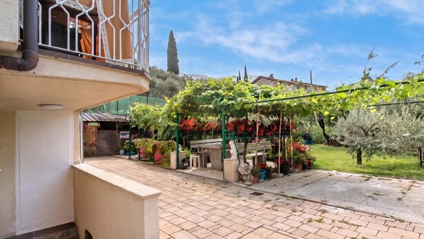 A courtyard with a pergola covered in grapevines, a bench, and a statue. - Falesia Vertical Rock View (Arco)