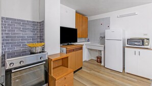 A compact kitchen with a brick wall backsplash, a stove, a sink, and a microwave. - Falesia Vertical Rock View (Arco)