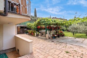 A courtyard with a pergola covered in grapevines, a bench, and a statue. - Falesia Vertical Rock View (Arco)