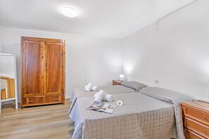 A bedroom with a double bed, a wooden wardrobe, a bedside table with a lamp, and a small nightstand. - Falesia Vertical Rock View (Arco)