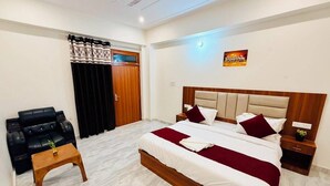 A hotel room with a bed, a small table, a sofa, and a ceiling fan. - Hotel Platinum Crown (Ayodhya)