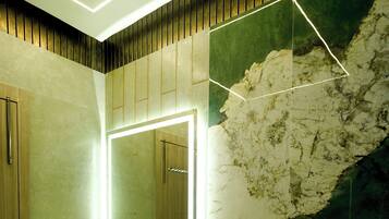 Un bagno dal design moderno, con uno specchio grande, un lavabo e una parete dall'aspetto marmorizzato.