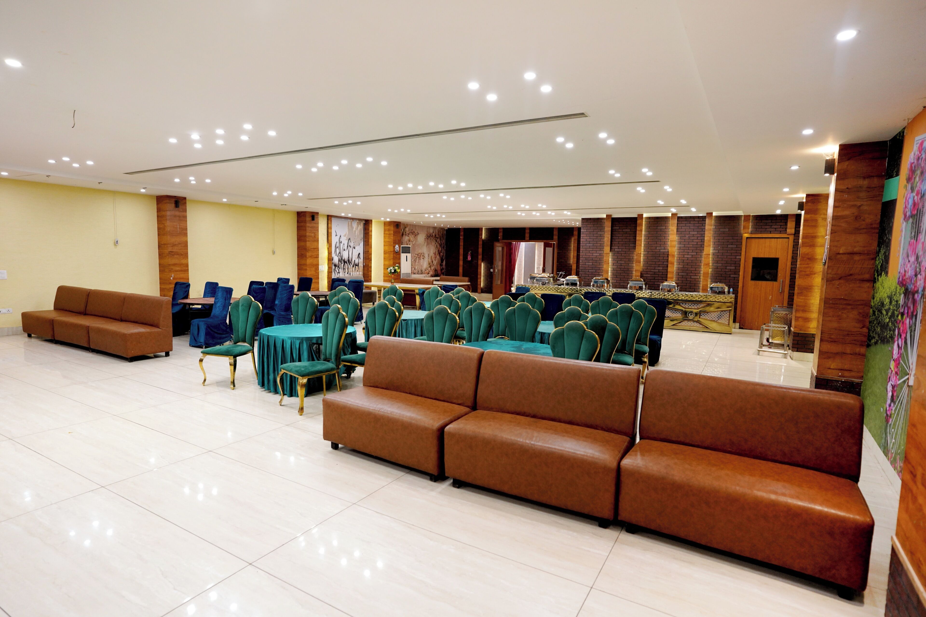 A spacious conference room with rows of green chairs, a stage, and a long table with a speaker system.