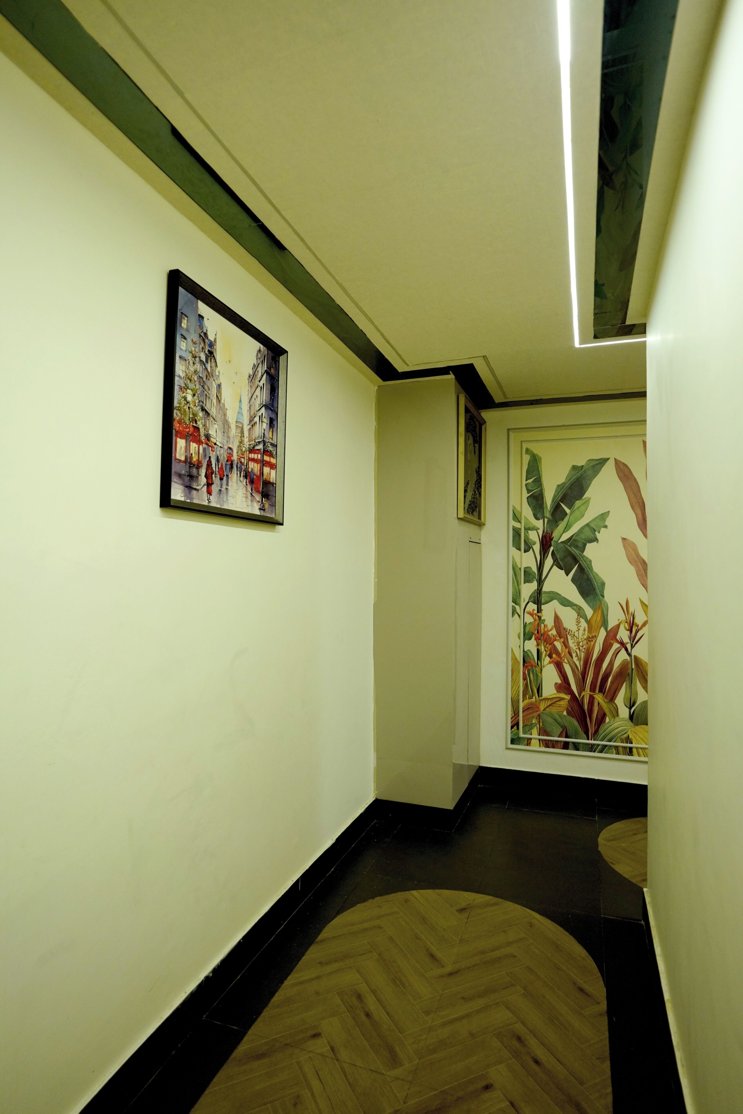 A hallway with a wooden floor, a painting of a street scene, and a door with a plant illustration.