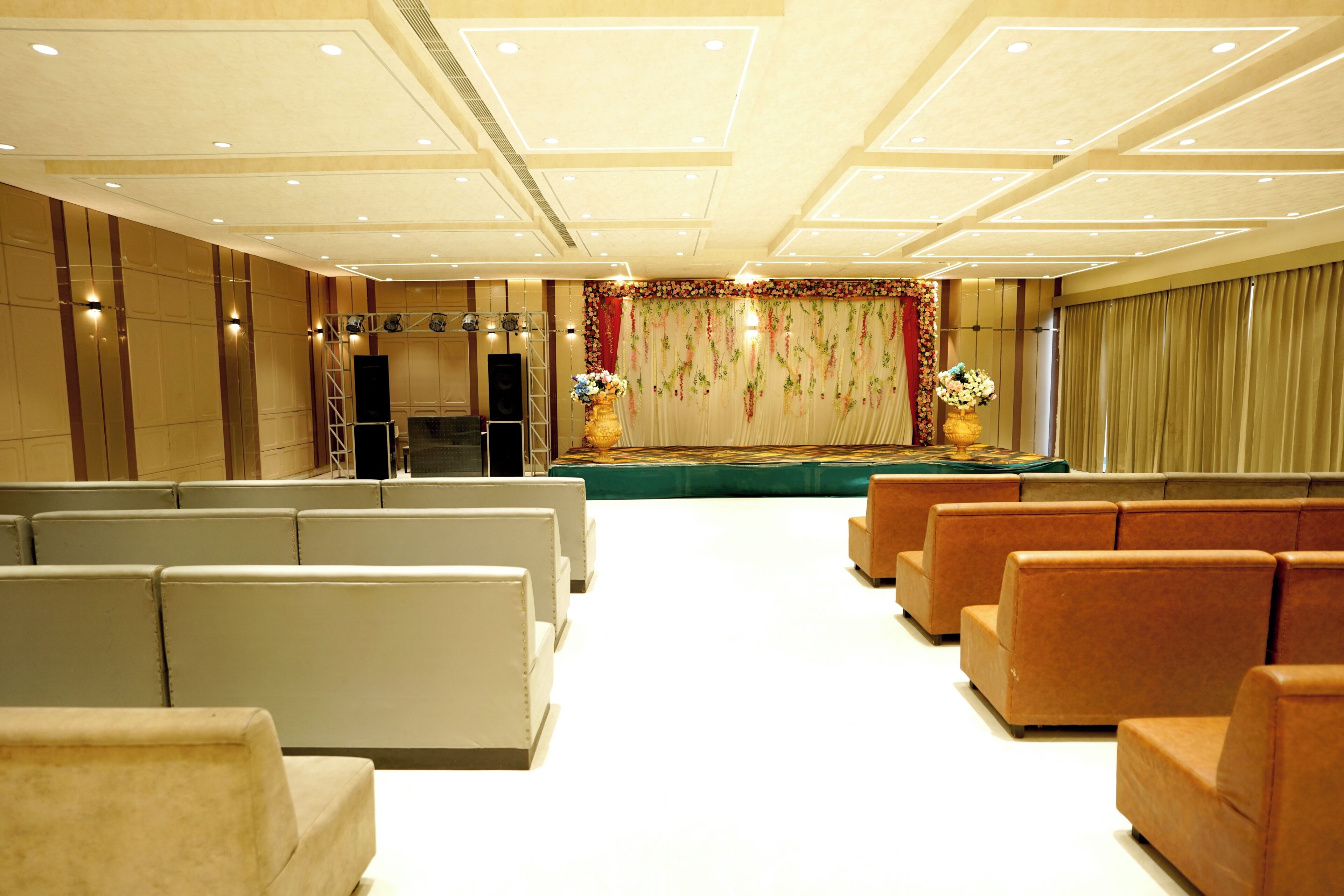 A spacious hall with tiered seating, a stage with floral decorations, and a sound system.