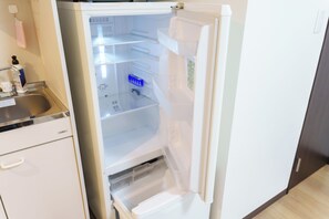 Ett kök med ett vitt kylskåp, en diskho i rostfritt stål och ett vitt skåp.