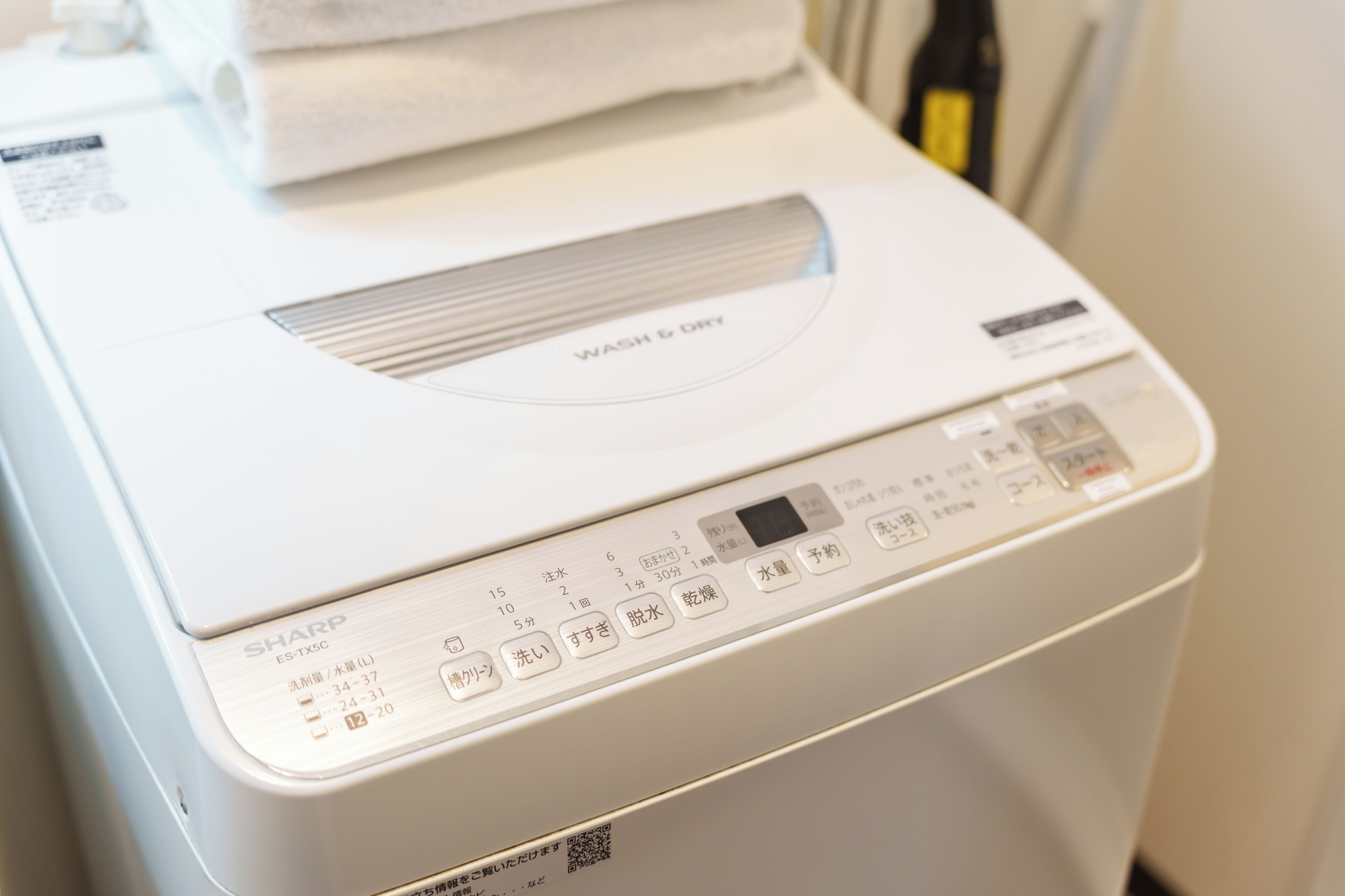 Vue de face d’un lave-linge blanc, avec un panneau de commande et une étiquette indiquant « LAVER » et « SÉCHER ».