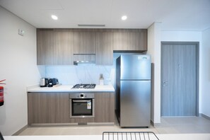 A modern kitchen with a built-in oven, a stainless steel refrigerator, and a gas stove. - Bloomfields 1BR in Vantage 2 - Yas Golf (Abu Dhabi)