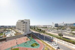 A multi-story building with a rooftop pool and a basketball court. - Bloomfields 1BR in Vantage 2 - Yas Golf (Abu Dhabi)