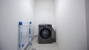 A laundry room with a washing machine and a drying rack. - Bloomfields 1BR in Vantage 2 - Yas Golf (Abu Dhabi)