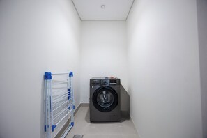 Ein Waschraum mit Waschmaschine und Wäscheständer.