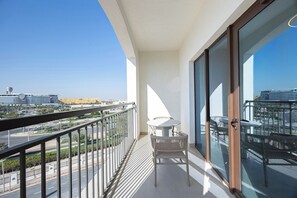 Ein Balkon mit Tisch und Stühlen, Blick auf eine Stadtlandschaft und einem klaren Himmel.