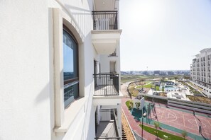 A residential building with balconies, a swimming pool, and a sports court. - Bloomfields 1BR in Vantage 2-YGC (Abu Dhabi)