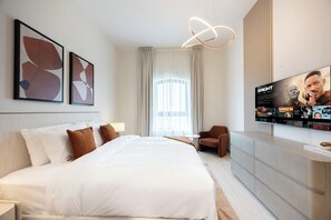 Une chambre d’hôtel avec un grand lit, un téléviseur diffusant un film et des œuvres d’art abstrait accrochées au mur.