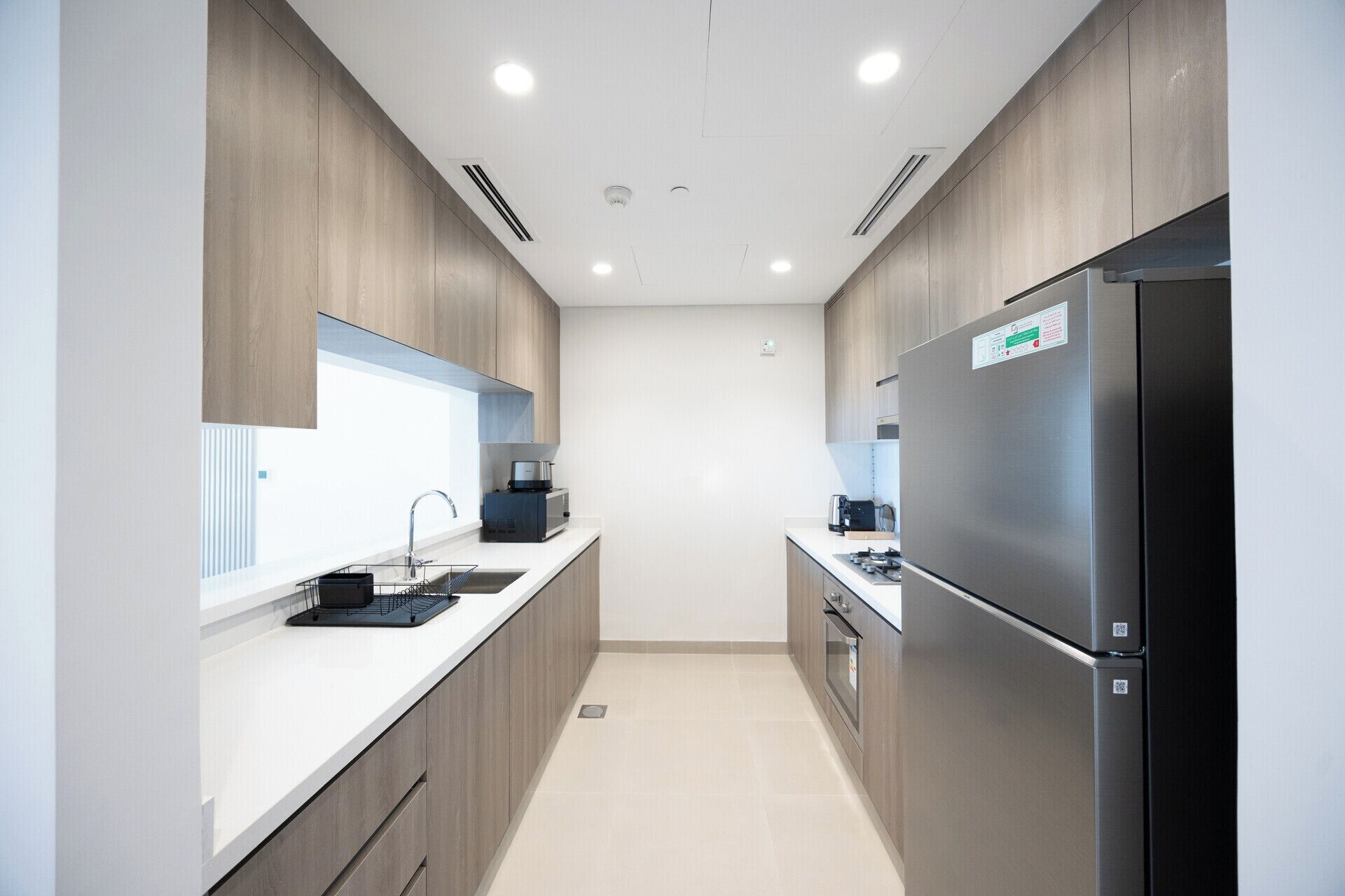 Una cocina moderna con un refrigerador de acero inoxidable, un horno empotrado y un microondas.