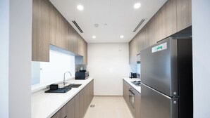 A modern kitchen with a stainless steel refrigerator, a built-in oven, and a microwave. - Bloomfields 1BR in Vantage 2 - Yas Golf (Abu Dhabi)