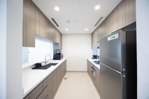 Eine moderne Küche mit einem Edelstahl-Kühlschrank, einem eingebauten Ofen und einer Mikrowelle.