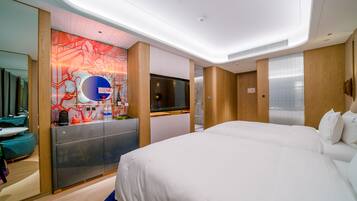 Quarto de hotel moderno com uma cama grande, televisão, minibar e banheiro com chuveiro.
