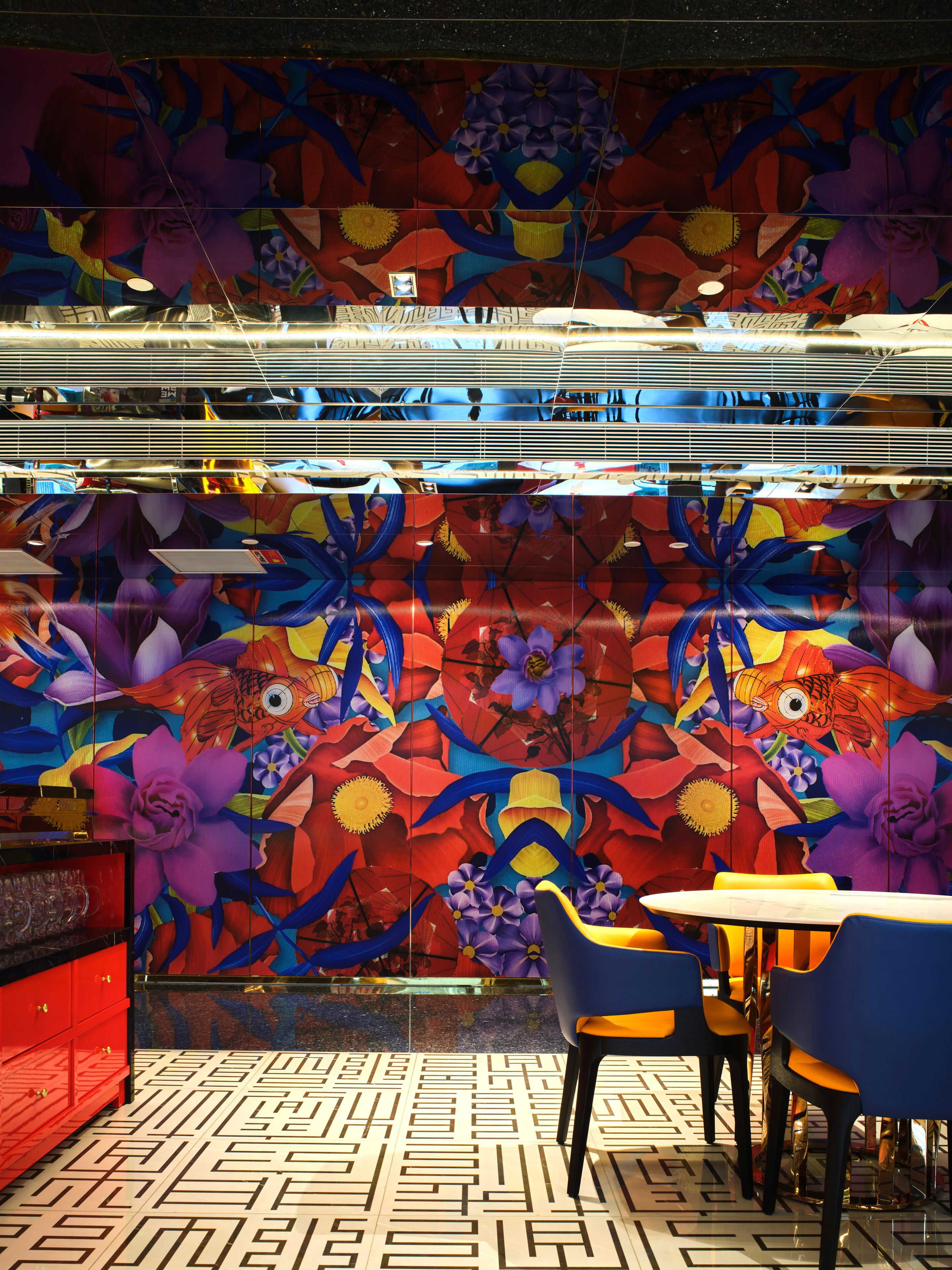 Una habitación con piso estampado, un armario rojo y un mural colorido con motivos florales y de peces.