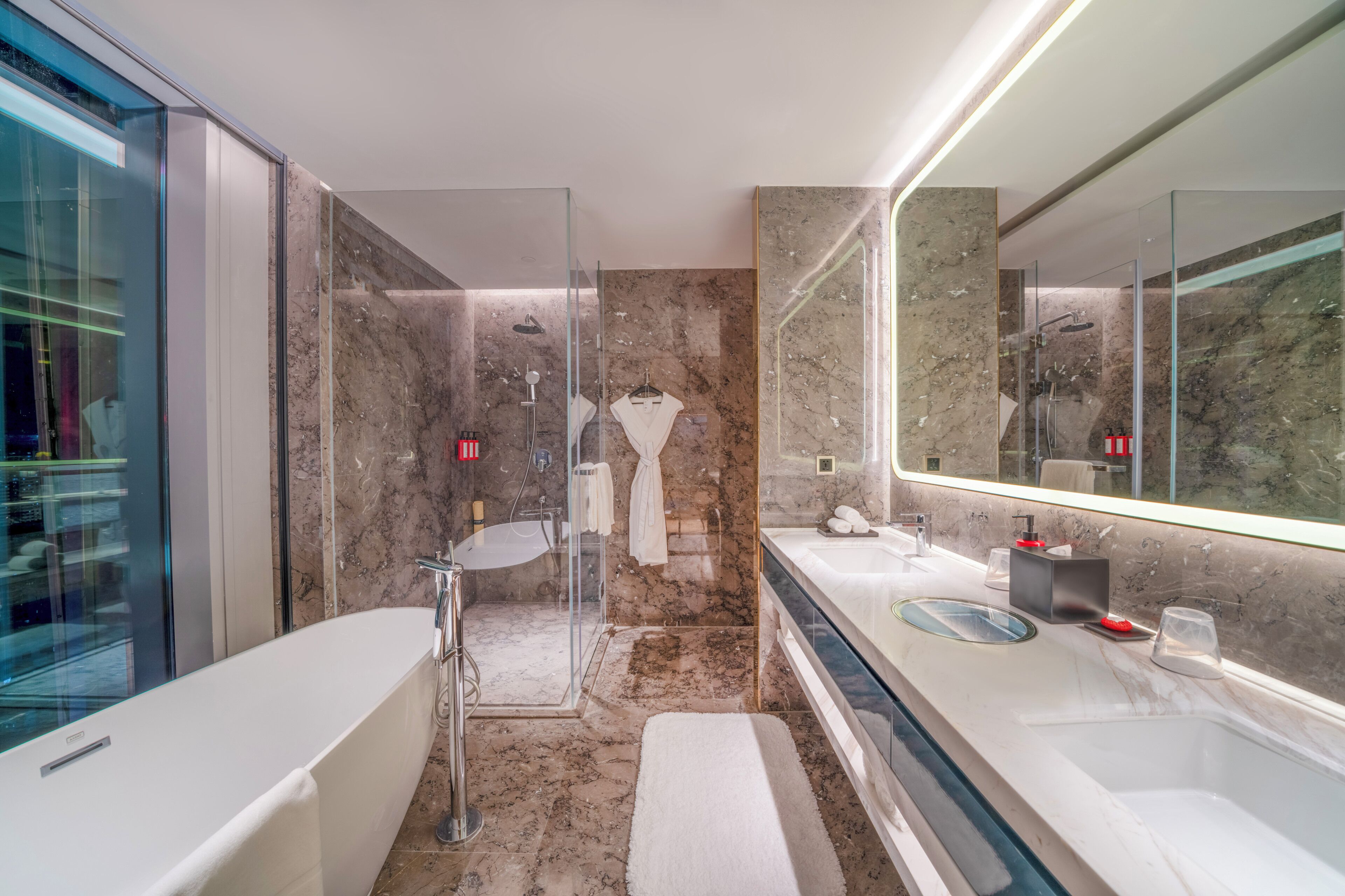 A modern bathroom with a glass-enclosed shower, a large mirror, and a dual sink vanity.