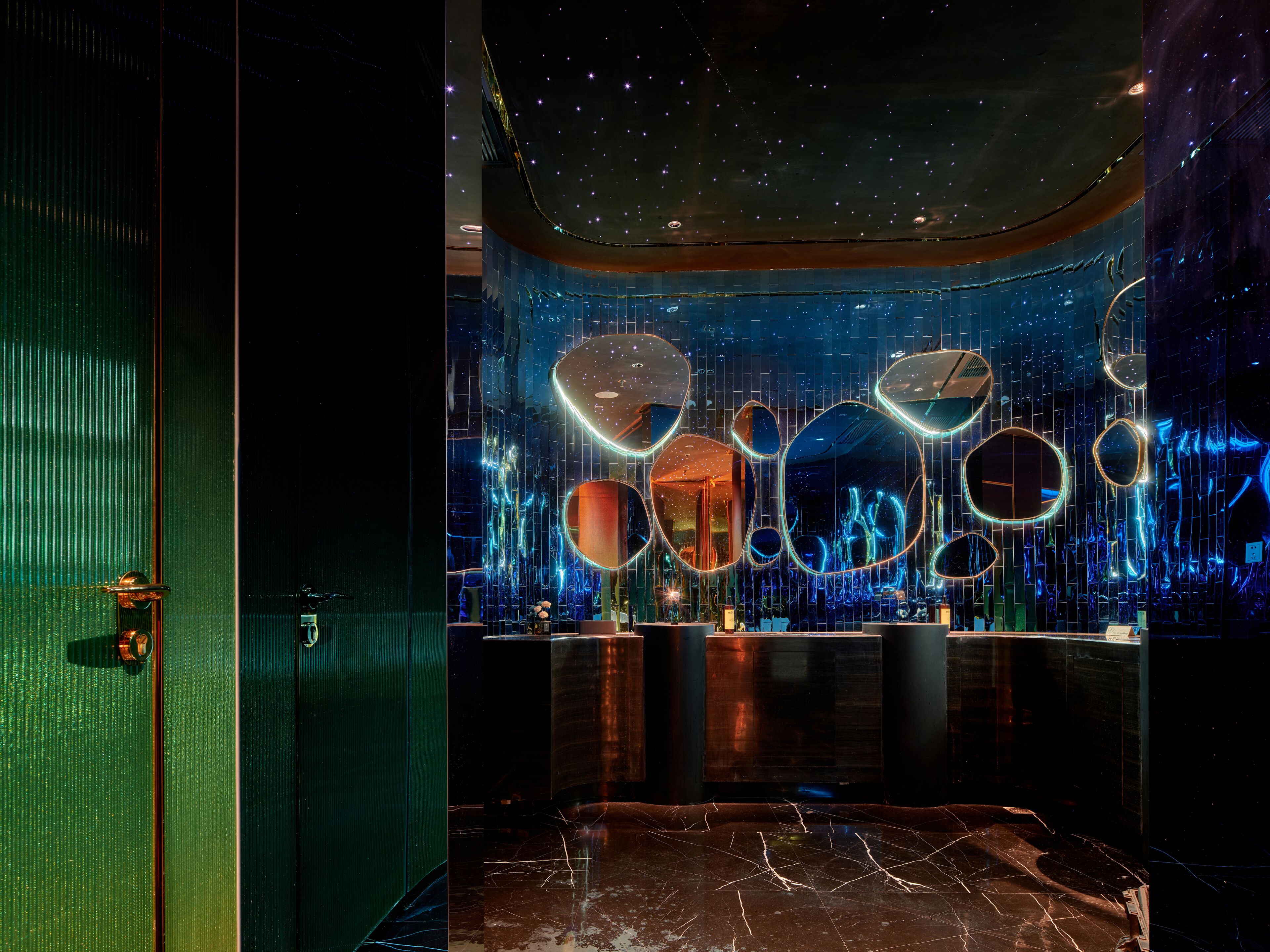 A modern interior with a reflective wall, a reception desk, and a marble floor.