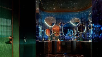 A modern interior with a reflective wall, a reception desk, and a marble floor.