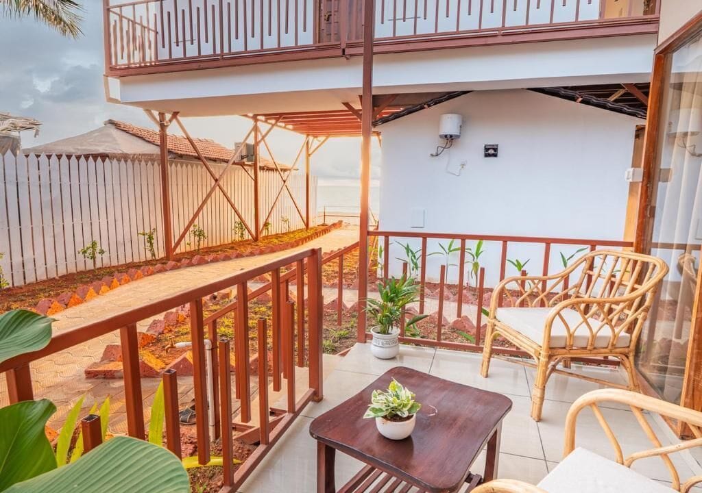 A balcony with a wooden railing, a table with a potted plant, and wicker furniture.