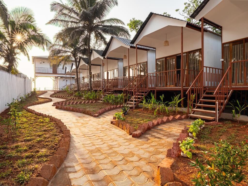 Un sendero conduce a una serie de habitaciones con barandas de madera y vistas a palmeras.