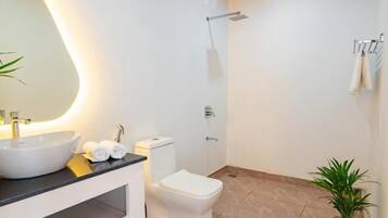 Un baño moderno con un espejo grande, un lavabo blanco, un inodoro y una ducha.