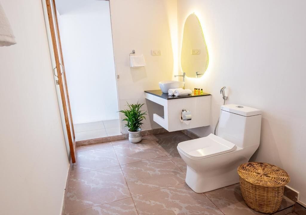 Un baño moderno con inodoro, lavamanos y espejo.