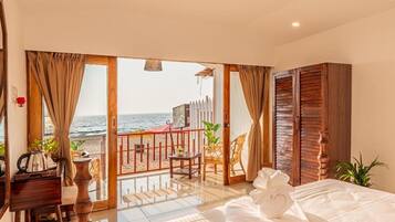 Habitación de hotel con balcón, cama con toallas ordenadas, armario de madera y vista al mar.