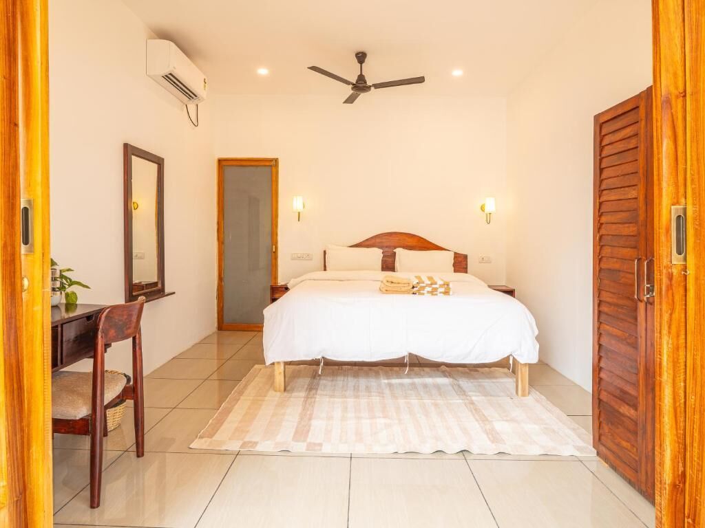 Un dormitorio con cama, mesitas de noche, ventilador de techo y puerta de madera.