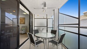 Ein moderner Innenraum mit Glastrennwand, einem runden Tisch mit Stühlen und einem Deckenventilator.