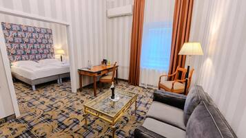 Quarto de hotel com cama, escrivaninha, cadeira, sofá e carpete estampado.