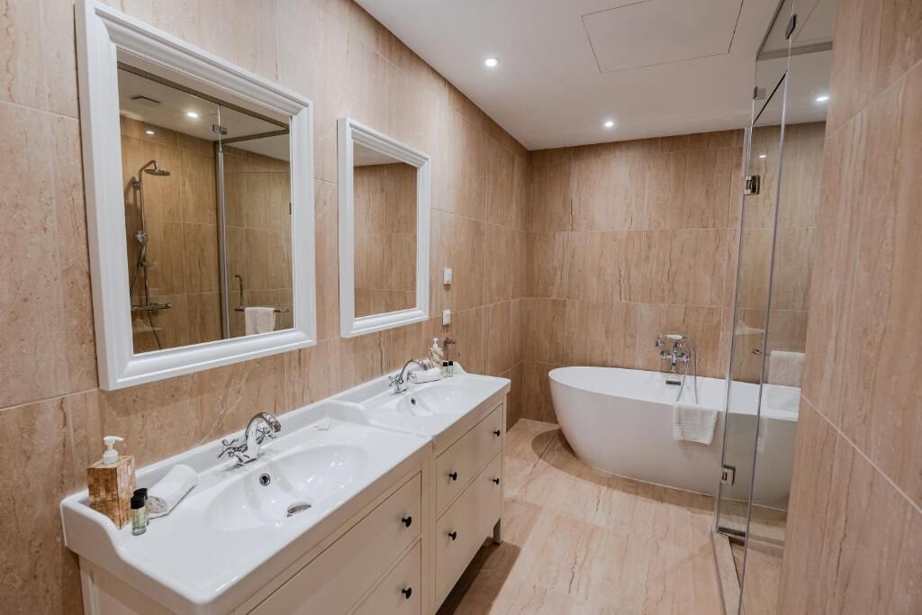 A modern bathroom with a freestanding bathtub, a double sink vanity, and a glass-enclosed shower area.