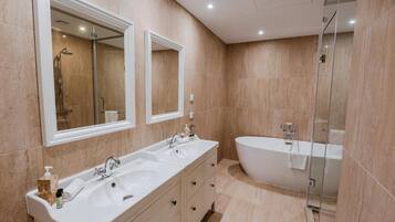 Ein modernes Badezimmer mit einer freistehenden Badewanne, einem Doppelwaschtisch und einer separaten Duschkabine.