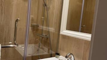 Ein Badezimmer mit einer Duschkabine, einem weißen Waschbecken und einem Spiegel darüber.